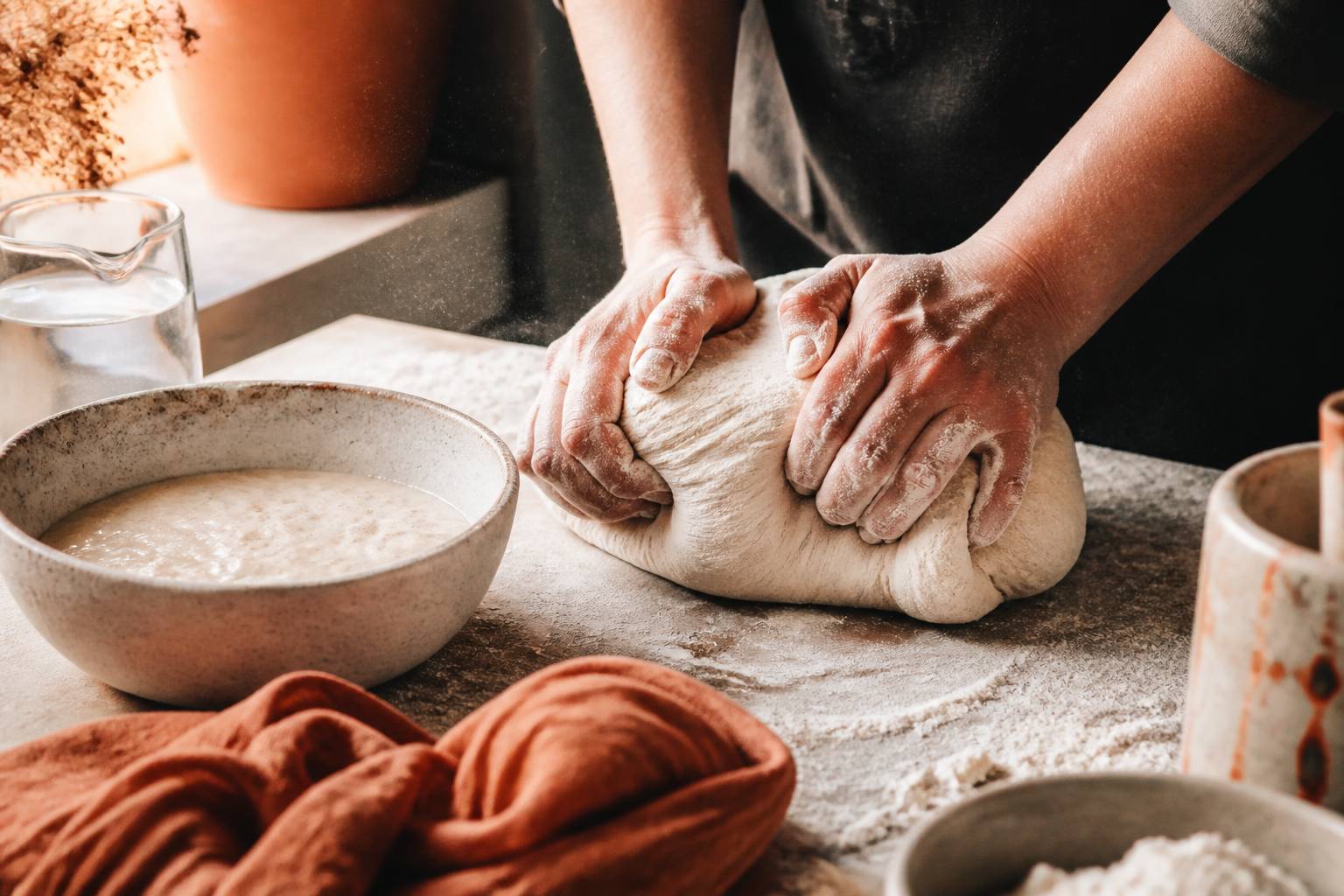 Mains pétrissant une boule de pâte à pain sur plan de travail