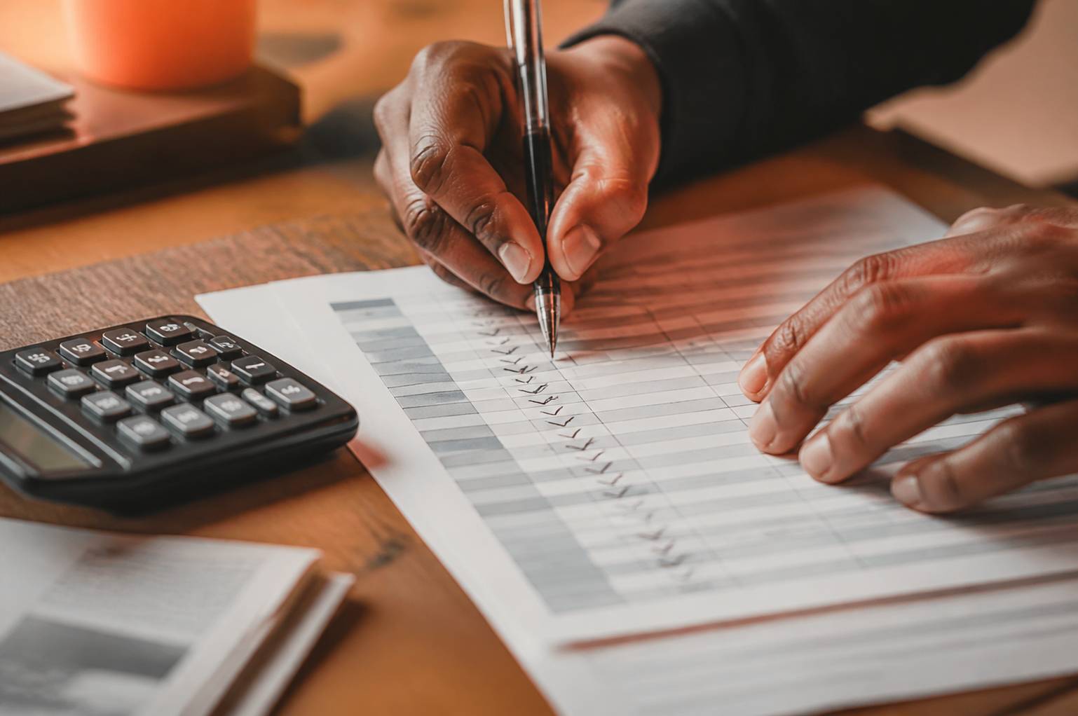 Mains cochant des lignes sur un relevé bancaire avec une calculatrice