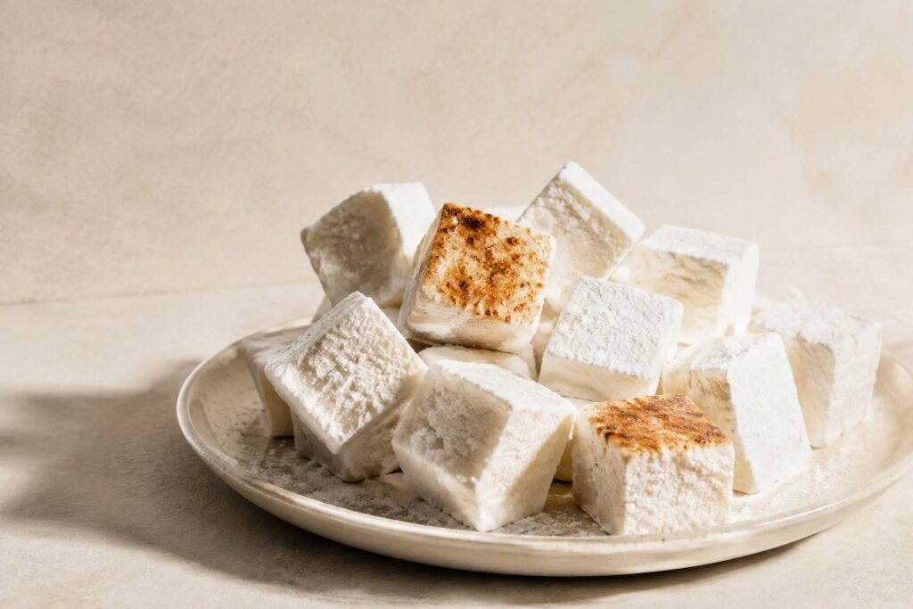Marshmallows maison cubiques poudrés de maïzena sur un plat clair